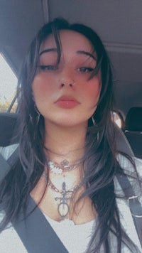 a woman in a car with long hair and a necklace