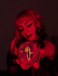 a woman holding a red crystal ball in her hand