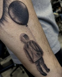 a black and grey tattoo of a boy holding a balloon
